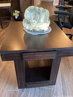 Full view of solid wood side table with drawer closed and natural art piece on top