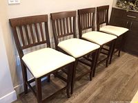 Front view of all four stools lined up against wall