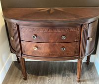 Frontal view of closed cabinet showing curved contour, drawers and side doors