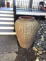Full view of large ceramic planter standing outdoors near rock landscaping and stairs showing its size and textured grid pattern