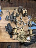 Overall group of antique sconces on wooden table showing variety in design and materials.