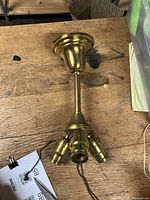Overall view of antique brass three light ceiling fixture showing canopy, stem, and three light sockets with pull chain switches.