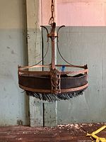 Front view of the brass chandelier showing the detailed metalwork, curved arms, and fringed dark fabric shade hanging from a chain.