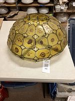 Dome-shaped amber glass panel ceiling shade on a table, showing overall shape and condition.