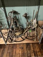 Collection of chandelier parts including frames, arms, and hanging rods on a wooden shelf