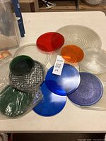 Assortment of round colored glass lenses displayed on table in red, amber, green, blue and clear finishes