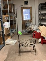 Front view of wrought iron floor lamp base showing round scrolls and heart shapes with missing table top and curved lamp pole.