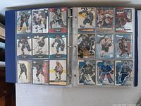 View of two binder pages showing multiple NHL hockey cards in protective sleeves. Cards are colorful and from the 2000s.