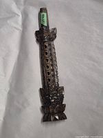 Flute showing the front side with multiple finger holes and intricate carved patterns along the length and ends.