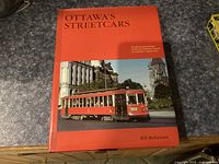 Front cover of the book showing a red streetcar in Ottawa with historic buildings in the background.