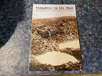 Front cover photo of the softcover book showing a WWII battlefield muddy scene with a soldier lying on the ground and water-filled craters.