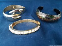 Overview of the three bracelets: silver-tone fold center clasp bracelet, gold-tone rhinestone bracelet, and multicolored glitter cuff bracelet.