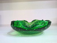 Side view of the green glass bowl showing the wavy rim and bubbled glass texture.