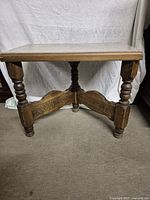 Full front view of vintage walnut table showing marble top and turned carved wooden legs with decorative carved stretcher connecting the legs