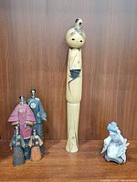 Overview showing all items: wooden doll, resin figurine group, porcelain geisha and folding fan