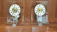 Pair of glass mantle clocks with round Roman numeral dials and silver dog silhouettes on glass panels.