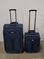 Two pieces of Ricardo Elite blue luggage, large and small, facing forward with handles extended against a white background.
