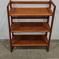 Front view of mid century teak bookshelf with three shelves.