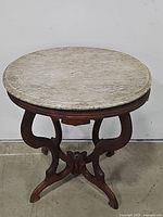 Front view showing carved wooden base and marble top of Victorian side table.