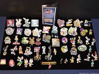 Full display of 58 Disney trading pins featuring characters Daisy Duck, Minnie Mouse, and Hidden Mickey designs laid out on black surface.