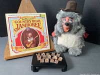 Full view of the vinyl album cover, plush bear with hat, and pins laid out together.