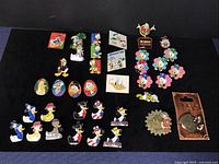 Full view of 37 Disney Ducks trading pins laid out on black cloth background showing various designs and characters.