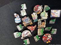 Overhead shot of the entire pin collection laid out on a black surface showing approximately 20 colorful Epcot Center themed pins including hidden Mickey designs and commemorative pins.