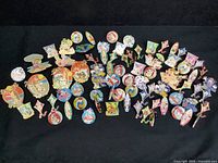 Wide layout of over 50 Disney trading pins spread out on a black surface, displaying various characters and beach themes.