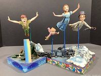 Both figurine sets displayed side by side on grey background