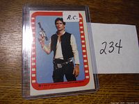 Front view of the Han Solo trading card in protective sleeve showing the character holding a blaster with red and white border.