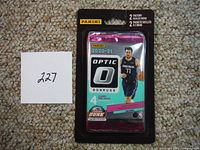 Photo of two unopened factory sealed packs of 2020-21 Panini Donruss Optic basketball cards, each pack containing 4 cards, featuring Luka Doncic on front.