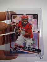 Front side of 2023 Donruss Clearly C.J. Stroud rookie card held by hand in a protective plastic sleeve showing the card's design and condition.