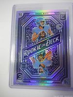 Front view of holographic Drake Maye rookie card in protective case.