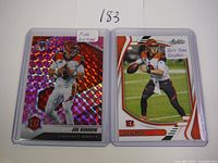 Two Joe Burrow 2nd year football cards side by side in protective sleeves, one pink prizm on left, one green foil on right.