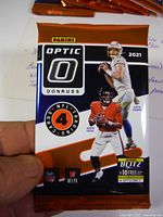 Front of the factory sealed pack showing players Justin Herbert and Justin Fields with Panini Optic Donruss branding and 4 cards included.