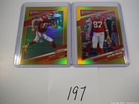 Two Travis Kelce football cards displayed side by side in protective sleeves, showing their holographic gold foil backgrounds and vibrant colors.