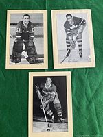 Photo of three vintage black and white hockey player photos on beige mounting card featuring Charlie Hodge, Bob Baun, and Jean Beliveau