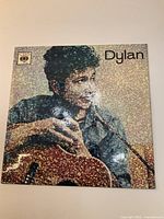 Front cover of Bob Dylan 45 RPM record showing a portrait of Bob Dylan with a guitar.