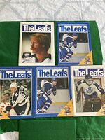 Five vintage Toronto Maple Leafs game programs arranged on green background, covers showing various players.