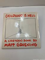 Front cover of 'Childhood is Hell' cartoon book showing character in corner and title text.
