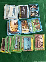 Vintage 1980s non-sports trading cards including Star Wars, Raiders of the Lost Ark, and E.T. arranged on green surface.