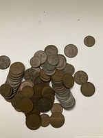 Pile of old British pennies and half pennies in various conditions spread on a white surface