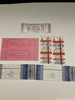 Photo showing all seven tickets arranged in two rows: upper row displays Robert Plant ticket, two pink Teenage Head tickets, two red and white The Kinks tickets; lower row displays two Cheap Thrills tickets.