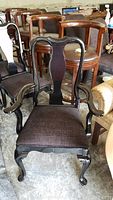 Front view of a black lacquered Queen Anne style captains chair with upholstered seat and armrests.