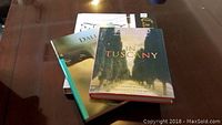 Three books stacked on a table: 'In Tuscany', 'Dali', and the calligraphy instruction booklet.