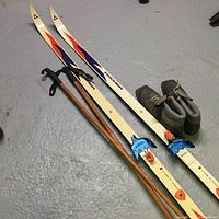 Fisher cross country skis with poles and boots on concrete floor, showing color and bindings details