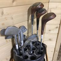 View of golf irons and woods in bag showing club heads and shafts