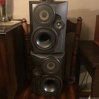 Two large RCA branded speakers stacked on chair showing front drivers and bass port