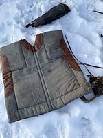 Photo of fabric saddle pad with brown accents laid out on the snow showing wear and tear.