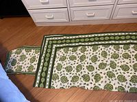 Photo of the 80x15 inch green artichoke table runner showing the length and detailed pattern.